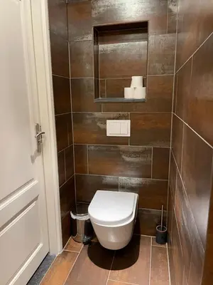 a bathroom with a toilet in a brown tiled wall at Annet's Studio in Zandvoort