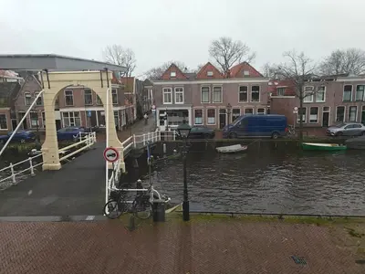 a bike parked next to a river with buildings at Alkmaar canal apartment in Alkmaar
