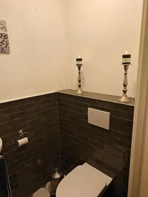 a bathroom with a toilet with two candles on the wall at Alkmaar canal apartment in Alkmaar