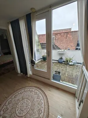 an open door with a view of a courtyard at Alkmaar canal apartment in Alkmaar