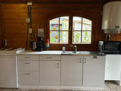 a kitchen with white cabinets and a sink and a window at De Narcis in Lisse