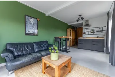 a living room with a black leather couch and a table at Grandioso Appartement - Studio in Castricum