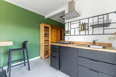 a kitchen with green walls and a sink and a chair at Grandioso Appartement - Studio in Castricum
