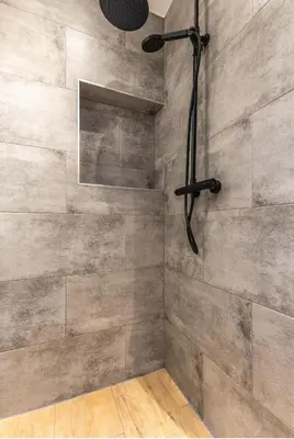 a shower with a stone wall with a shower head at Grandioso Appartement - Studio in Castricum