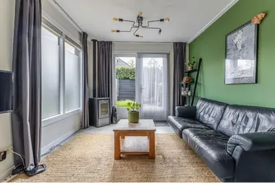 a living room with a black leather couch and a table at Grandioso Appartement - Studio in Castricum