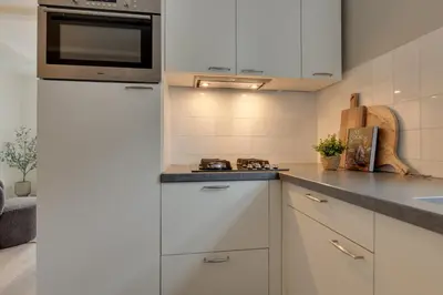 a kitchen with white cabinets and a microwave at Boutique Hoeve de Berg in Uitgeest