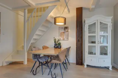 a dining room with a table and chairs and stairs at Boutique Hoeve de Berg in Uitgeest