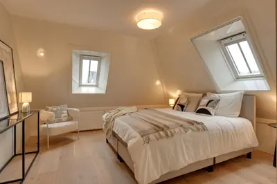 a bedroom with a large bed and two windows at Boutique Hoeve de Berg in Uitgeest