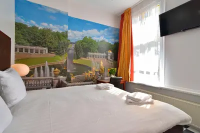 a bedroom with a large painting on the wall at Hotel La Belle Vue in Amsterdam