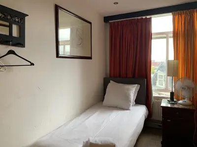 a bed in a room with a window and a bed sidx sidx sidx at Hotel La Belle Vue in Amsterdam