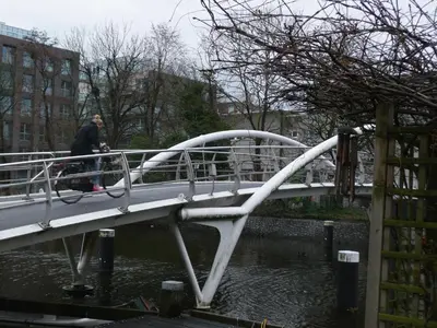 a man walking his dog on a bridge over the water at Hotel La Belle Vue in Amsterdam