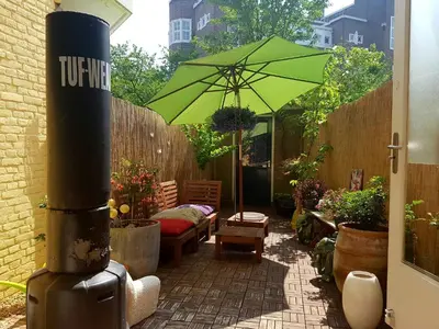 a patio with a green umbrella and a couch at Zoet Amsterdam in Amsterdam