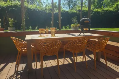 a wooden table with chairs and wine glasses on a deck at Juneberry Ecolodge Bergen in Bergen