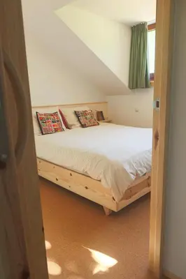 a bedroom with a wooden bed with pillows on it at Juneberry Ecolodge Bergen in Bergen