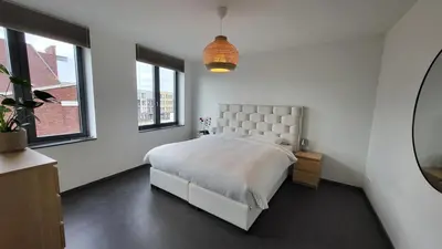 a white bedroom with a large bed and windows at B&B Kopwest 1 in Purmerend