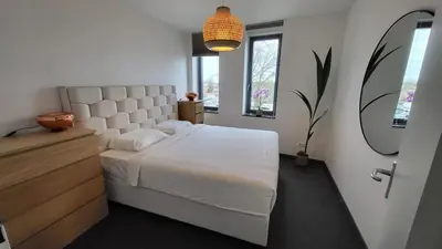 a bedroom with a large white bed and a mirror at B&B Kopwest 1 in Purmerend