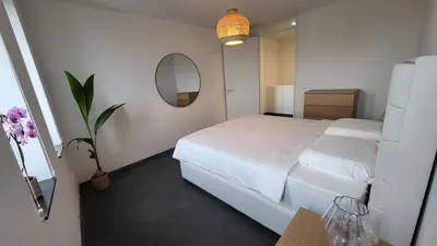 a bedroom with a white bed and a mirror at B&B Kopwest 2 in Purmerend