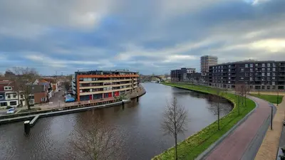 a river in a city with buildings and a bridge at B&B Kopwest 2 in Purmerend