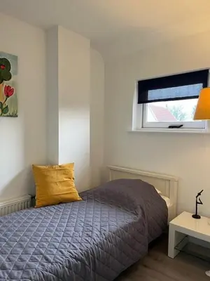 a bedroom with a bed with a yellow pillow and a window at Cozy 2 bedroom apartment in Maarssen