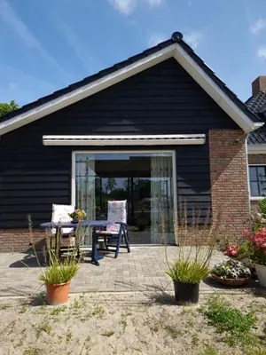 a black house with a patio with a table at De bloemenkwekerij in Egmond-Binnen