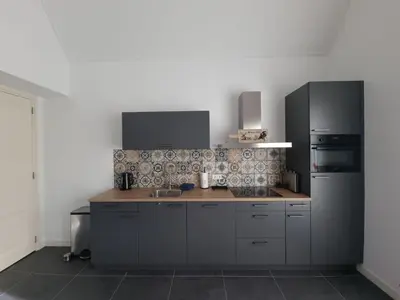 a kitchen with a wooden counter top and a black refrigerator at De bloemenkwekerij in Egmond-Binnen