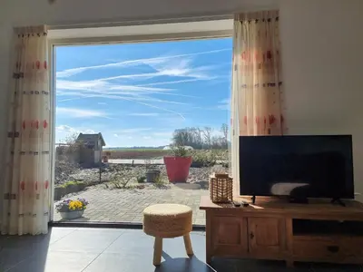 a living room with a tv and a large window at De bloemenkwekerij in Egmond-Binnen