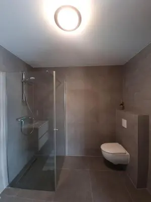 a bathroom with a toilet and a glass shower at De bloemenkwekerij in Egmond-Binnen