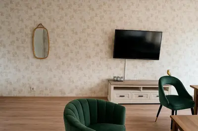 a living room with a television and a green chair at Reza Almere in Almere