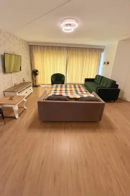 a bedroom with a bed and a couch and a tv at Reza Almere in Almere