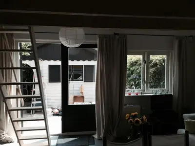 a living room with a ladder leading to a sliding glass door at Almost At The Beach in Wijk aan Zee