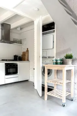 a kitchen with white cabinets and a wooden table at -Casa Como- nabij het meer, restaurants & keukenhof in Noordwijkerhout