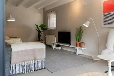 a bedroom with a bed and a desk with a tv at -Casa Como- nabij het meer, restaurants & keukenhof in Noordwijkerhout