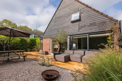 a patio with a couch and an umbrella at -Casa Como- nabij het meer, restaurants & keukenhof in Noordwijkerhout