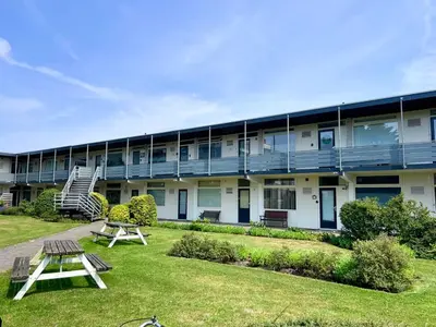 a building with two picnic tables in the yard at Reumann Holiday Apartments De Schelp 12 in Zandvoort