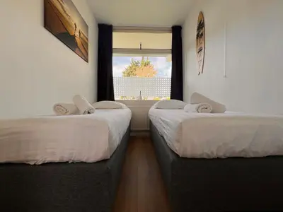 two beds in a room with a window at Reumann Holiday Apartments De Schelp 12 in Zandvoort