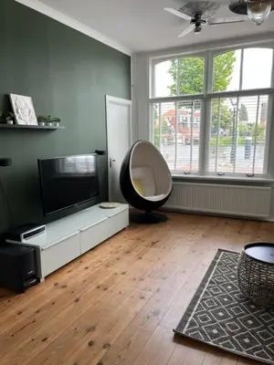 a living room with a chair and a flat screen tv at Appartement aan het water in Alkmaar