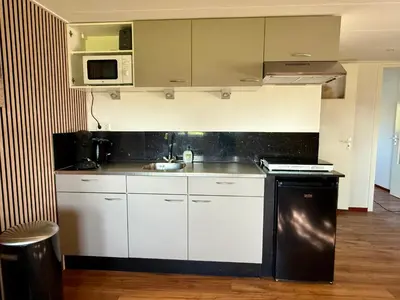 a kitchen with white cabinets and a black appliance at Holiday Home Vijfhuizen 2pers Lisa in Vijfhuizen