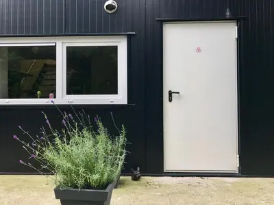 a black building with white doors and a cat sitting in front at Holiday Home Vijfhuizen 2pers Lisa in Vijfhuizen