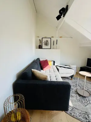 a living room with a black couch in a room at BeachHouse Oranje Nassau in Noordwijk aan Zee