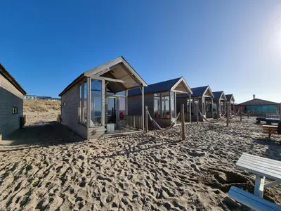a row of beach huts on a sandy beach at Strandvakantiehuisjes Katwijk in Katwijk aan Zee