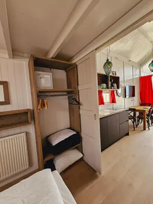 a room with a bed and a kitchen with a table at Strandvakantiehuisjes Katwijk in Katwijk aan Zee