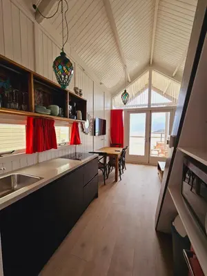 a large kitchen with a dining table and red curtains at Strandvakantiehuisjes Katwijk in Katwijk aan Zee