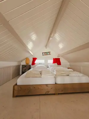 a bedroom with a large bed in a attic at Strandvakantiehuisjes Katwijk in Katwijk aan Zee