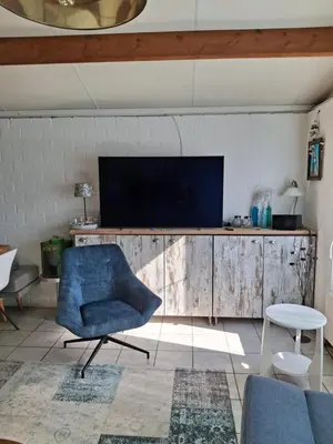 a living room with a blue chair and a television at Rekerlanden 211 in Schoorldam