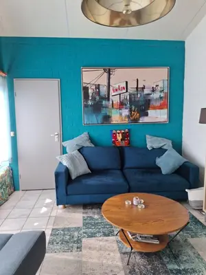 a living room with a blue couch and a table at Rekerlanden 211 in Schoorldam