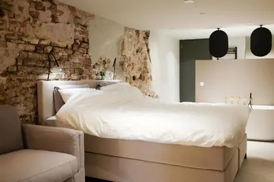 a bedroom with a large white bed and a chair at Domnacht aan de gracht in Utrecht