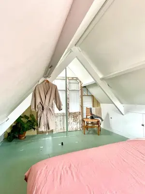 a bedroom with a pink bed and a chair at Boutique Canal house 't Jannetje - historical and cozy in Edam