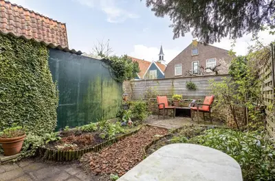 a backyard with a fence and a table and chairs at Boutique Canal house 't Jannetje - historical and cozy in Edam