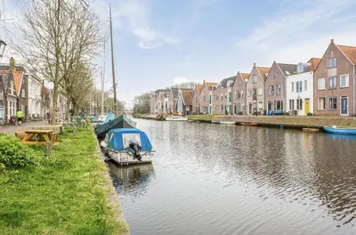 a boat on a river in a city with houses at Boutique Canal house 't Jannetje - historical and cozy in Edam