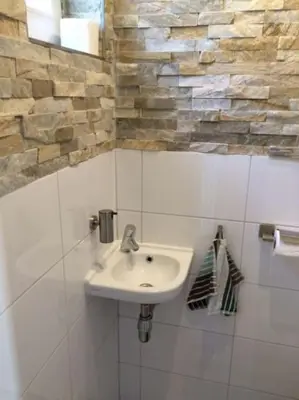 a bathroom with a sink in a white tiled wall at Nice and cosy house close Amsterdam and airport in Badhoevedorp